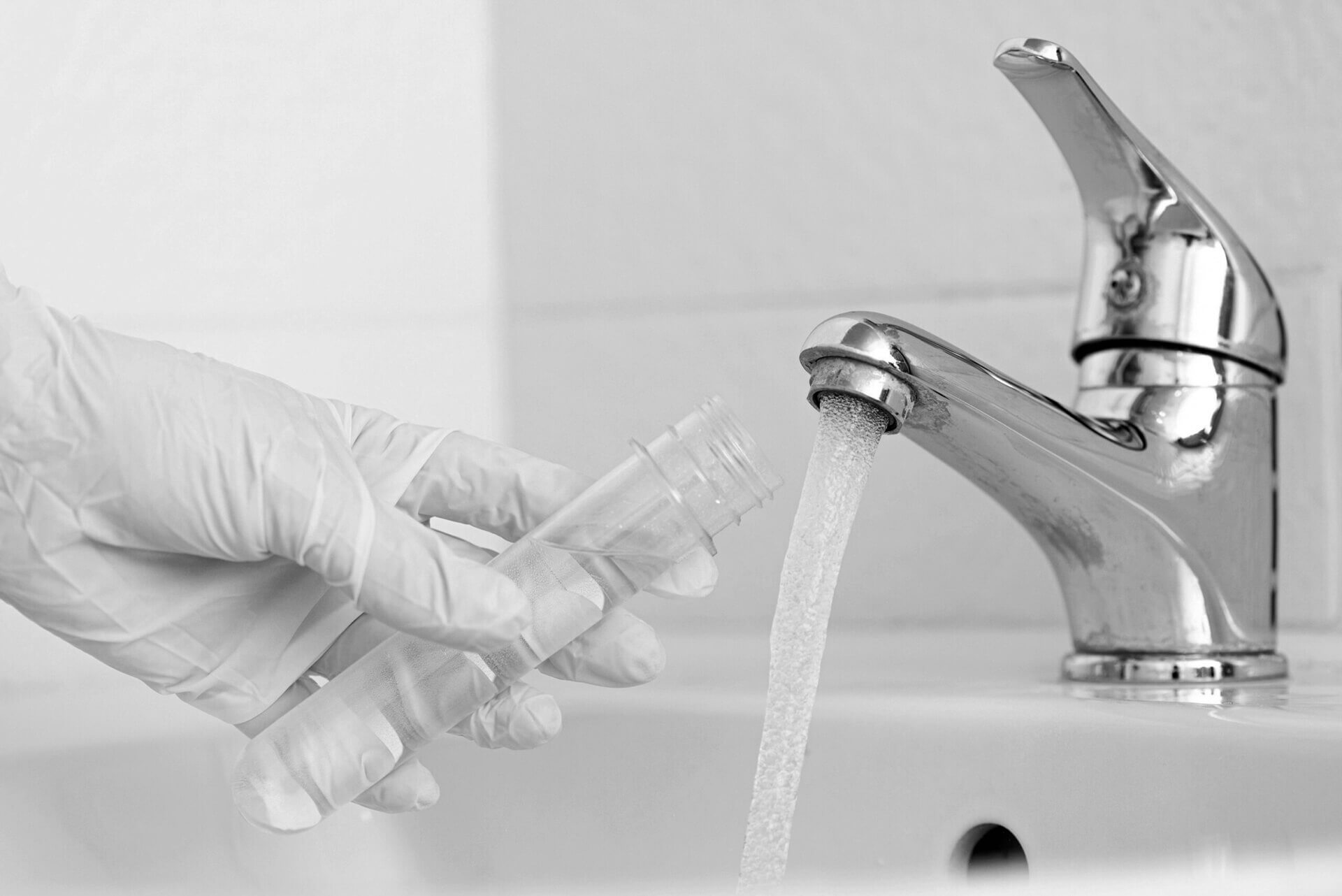 Tap water analysis quality control concept. Hand with a flask an